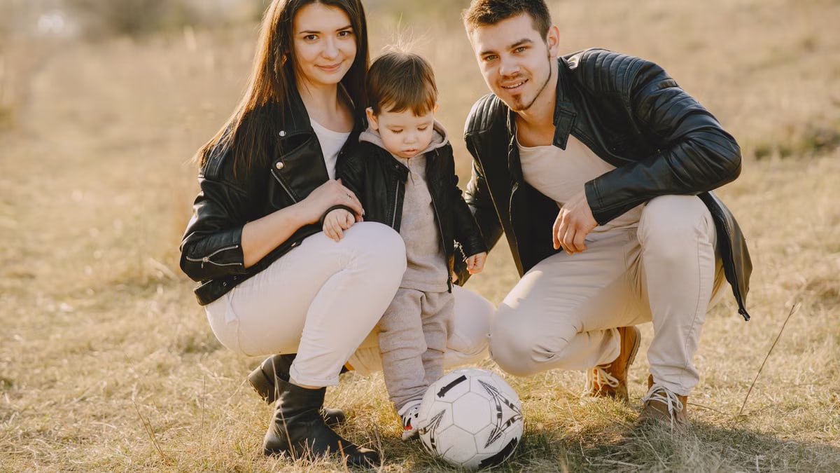 A family enjoys a warm day bonding and playing soccer outdoors in the park.